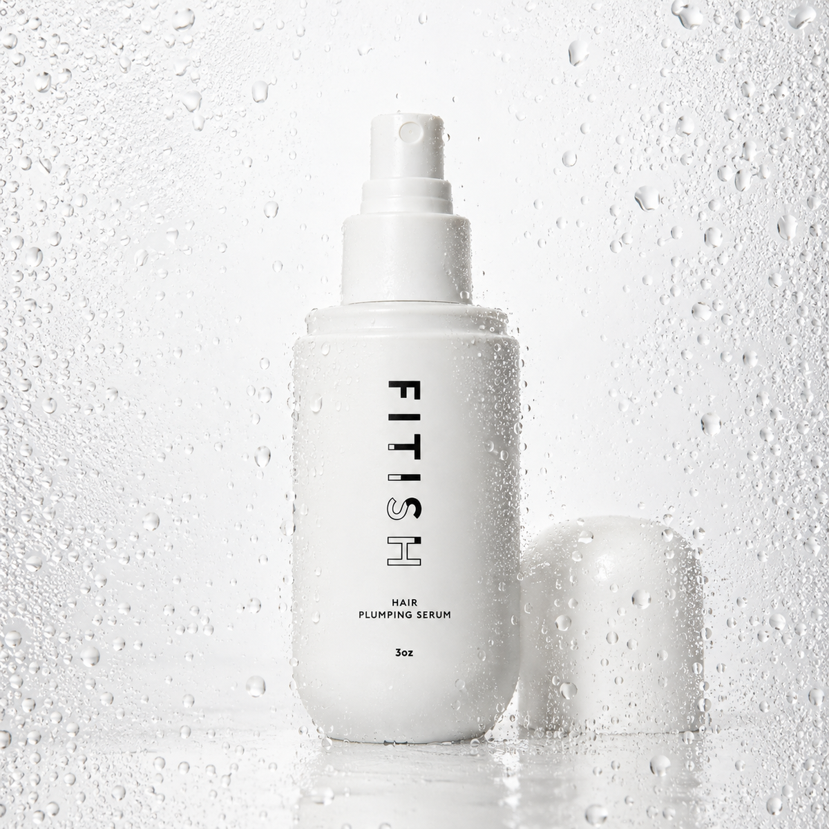 Fitish Hair Plumping Serum 3 oz spray bottle with cap off, surrounded by water droplets